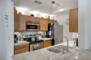 A modern kitchen with wooden cabinets, stainless steel appliances, and a granite countertop. - Poolside Resort Style Awesomeness (Phoenix)