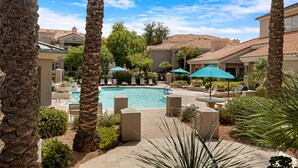 A pool area with lounge chairs and umbrellas, surrounded by palm trees and a clear sky. - Poolside Resort Style Awesomeness (Phoenix)