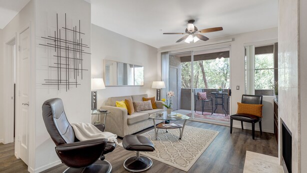 A modern living room with a sofa, a leather chair, a glass coffee table, and a fireplace. - Poolside Resort Style Awesomeness (Phoenix)