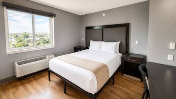 A hotel room with a large bed, bedside tables, a heater, and a view of the city.