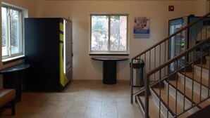 A stairwell with a metal railing, a trash can, and a window with a view of trees. - Welcome Suites Hazelwood (Hazelwood)