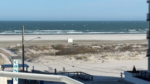 Vista da praia a partir de uma varanda, com área de estacionamento e uma placa com a inscrição 'CON'.