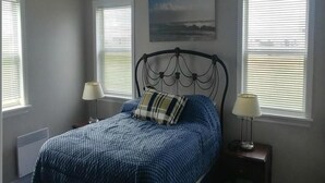 Quarto com uma cama, duas mesas de cabeceira e uma janela com persianas.
