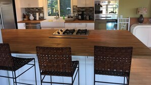 A modern kitchen with a central island, white cabinetry, and a large window.
