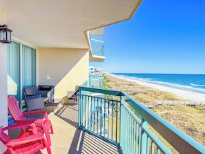 A balcony with a view of the beach, outdoor furniture, and a railing.
