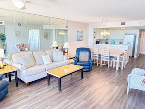 A modern living room with a sofa, coffee table, and a dining area with chairs and a table.