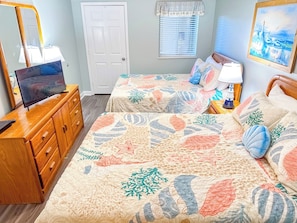 A bedroom with two beds, a wooden dresser, a desk with a computer, and a painting on the wall. - North Shore Villas 502 (North Myrtle Beach)