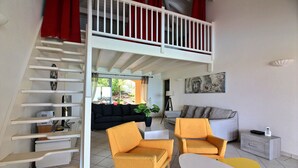 A living room with a staircase, two yellow armchairs, a white table, and a grey sofa. - Luxurious Caribbean Contemporary Charm with Breathtaking Panoramic Ocean View (Cul-de-Sac)