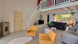 A spacious living area with a staircase leading to an upper level, a flat-screen TV, and a comfortable seating arrangement. - Luxurious Caribbean Contemporary Charm with Breathtaking Panoramic Ocean View (Cul-de-Sac)