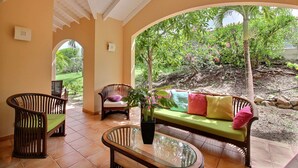 A covered patio with a wooden bench, a glass table, and a sofa with cushions. There is a potted plant on the bench. - Luxurious Caribbean Contemporary Charm with Breathtaking Panoramic Ocean View (Cul-de-Sac)