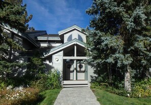 A two-story house with a front porch, a small garage, and a covered entryway. - Beautiful year-round Mammoth Townhome with 3 Bedrooms Plus Loft, 2 Bathrooms (Mammoth Lakes)