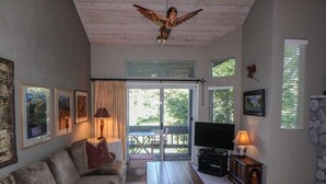 Ein Wohnzimmer mit einer Couch, einem Holztisch, einem Fernseher und einer Steinwand.