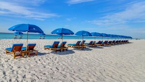 Ein Strand mit blauen Sonnenschirmen und Holzliegen.
