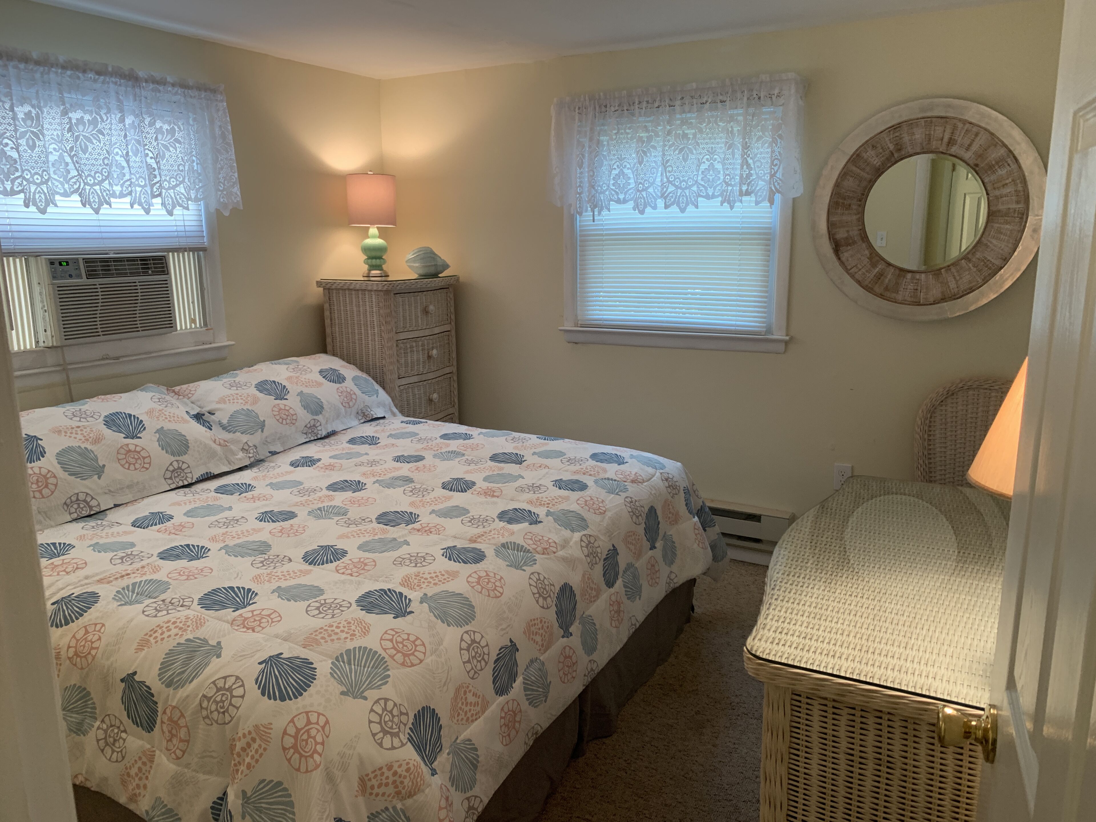 Une chambre à coucher avec un lit, une commode, une lampe, un miroir et un radiateur.
