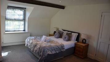 A bedroom with a bed, bedside tables, a window with blinds, a radiator, and a door.