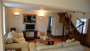 A living room with a sofa, a coffee table, and a television. There is a staircase leading to another level. - The Coachhouse (Scarborough)