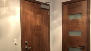 Zwei Holztüren mit modernem Design, inklusive Griff und Schlüsselloch, in einer Diele mit einer Leuchte darüber.