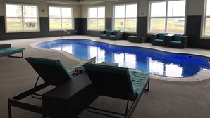 Ein Hallenbad mit Liegestühlen und Blick ins Freie.