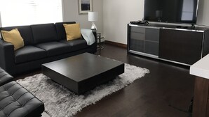Ein modernes Wohnzimmer mit einem schwarzen Sofa, einem Couchtisch und einem Fernseher auf einem Schrank.