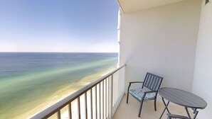 Un balcone con vista sull'oceano, una sedia e un tavolino.