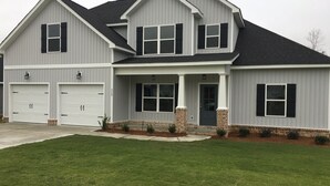 Une maison à deux étages avec un garage, un porche à l’avant et une pelouse bien entretenue.