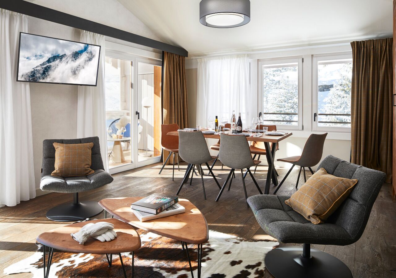Una sala de estar moderna con chimenea, un comedor con mesa y sillas, y un ventanal con cortinas.
