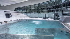 An indoor swimming pool with a glass wall and snowy surroundings. - Ecrin Blanc Resort Courchevel (Courchevel)