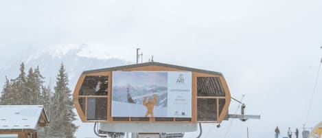 A ski lift station with a wooden building and a snow-covered landscape.