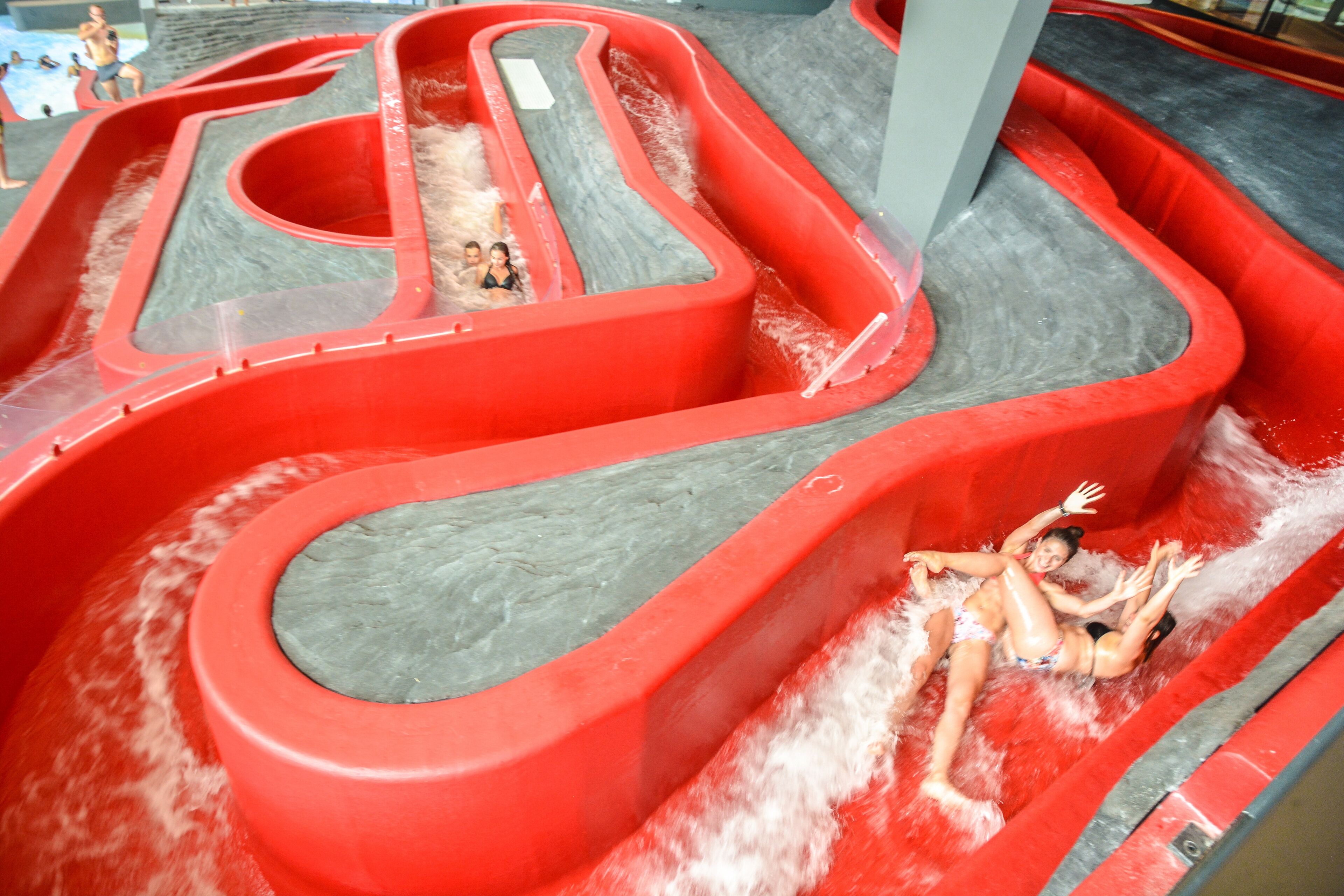 Un parque acuático con varias toboganes de agua rojos y piscinas.
