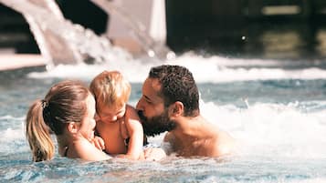 A family in a hot tub with water jets, surrounded by a pool area.