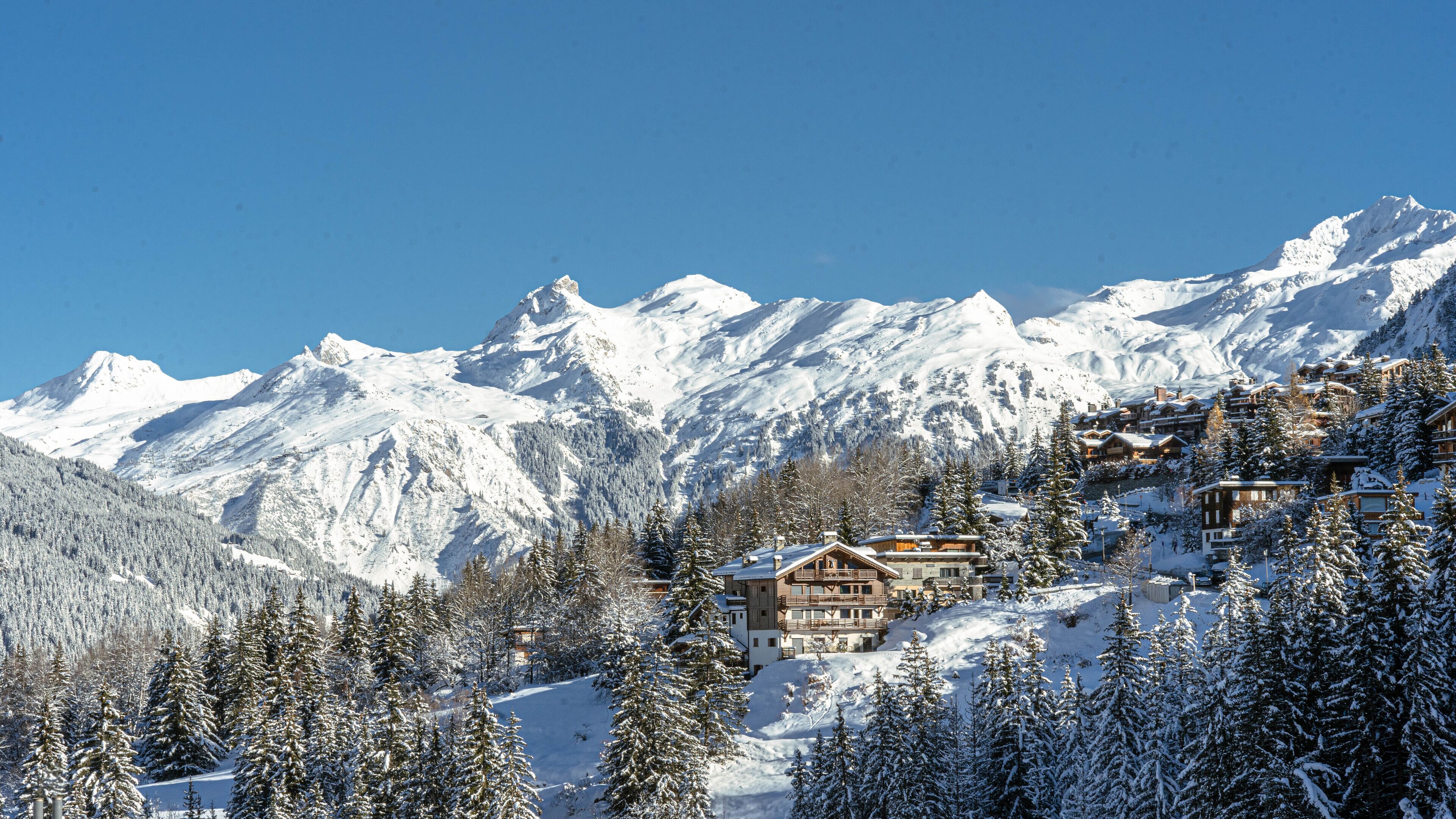 A snow-covered mountain with a chalet-style building nestled among trees.