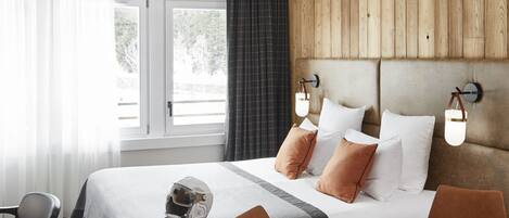 A hotel room with a bed, a dining table with a cup and teapot, a chair, and a cowhide rug.