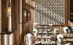 A restaurant interior with wooden walls, framed pictures, and a long dining table with chairs. - Ecrin Blanc Resort Courchevel (Courchevel)