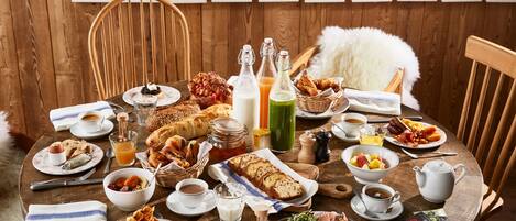 A wooden dining table with breakfast items, including bread, pastries, and beverages.