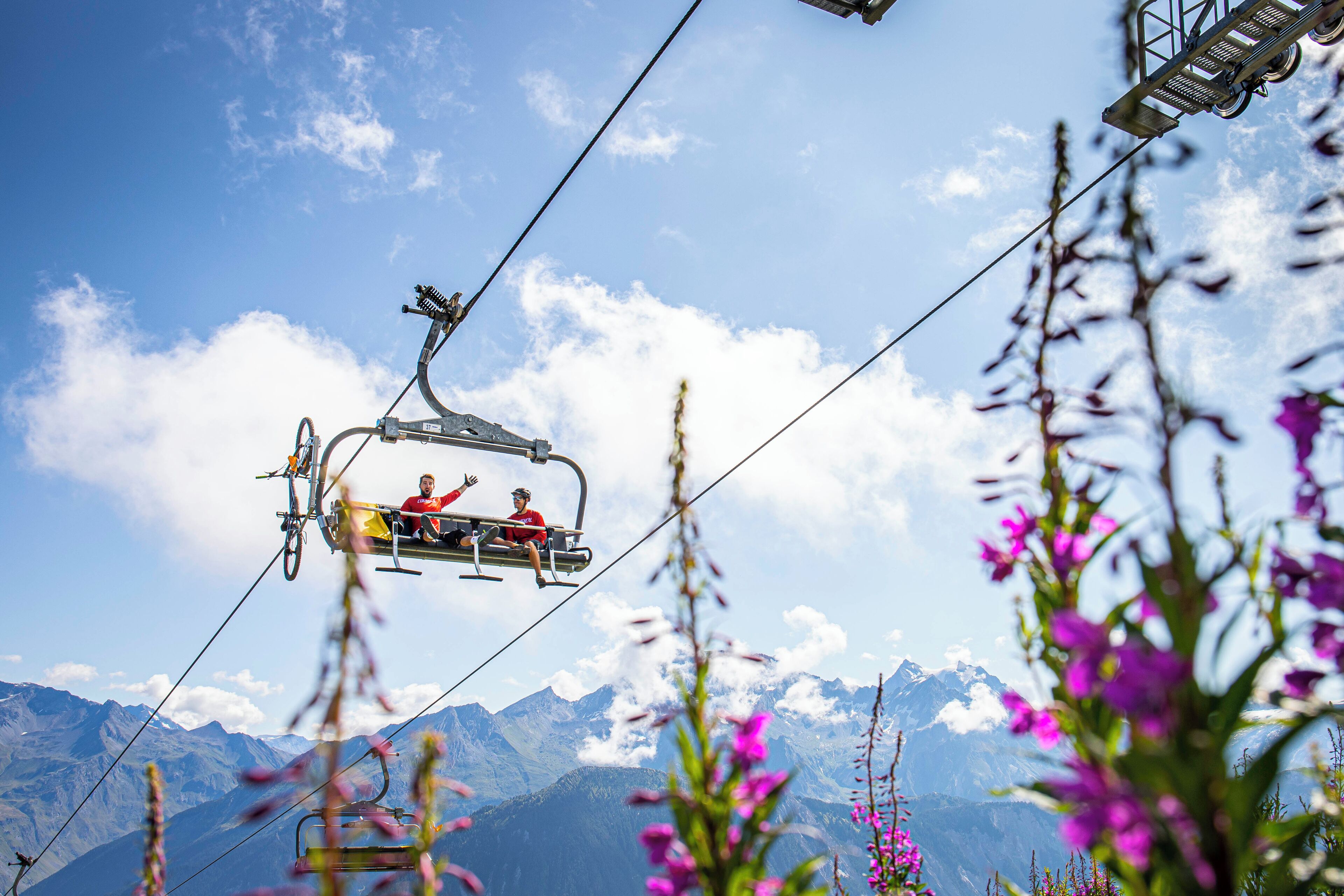 Un télésiège avec des passagers, un paysage montagneux et un ciel dégagé.