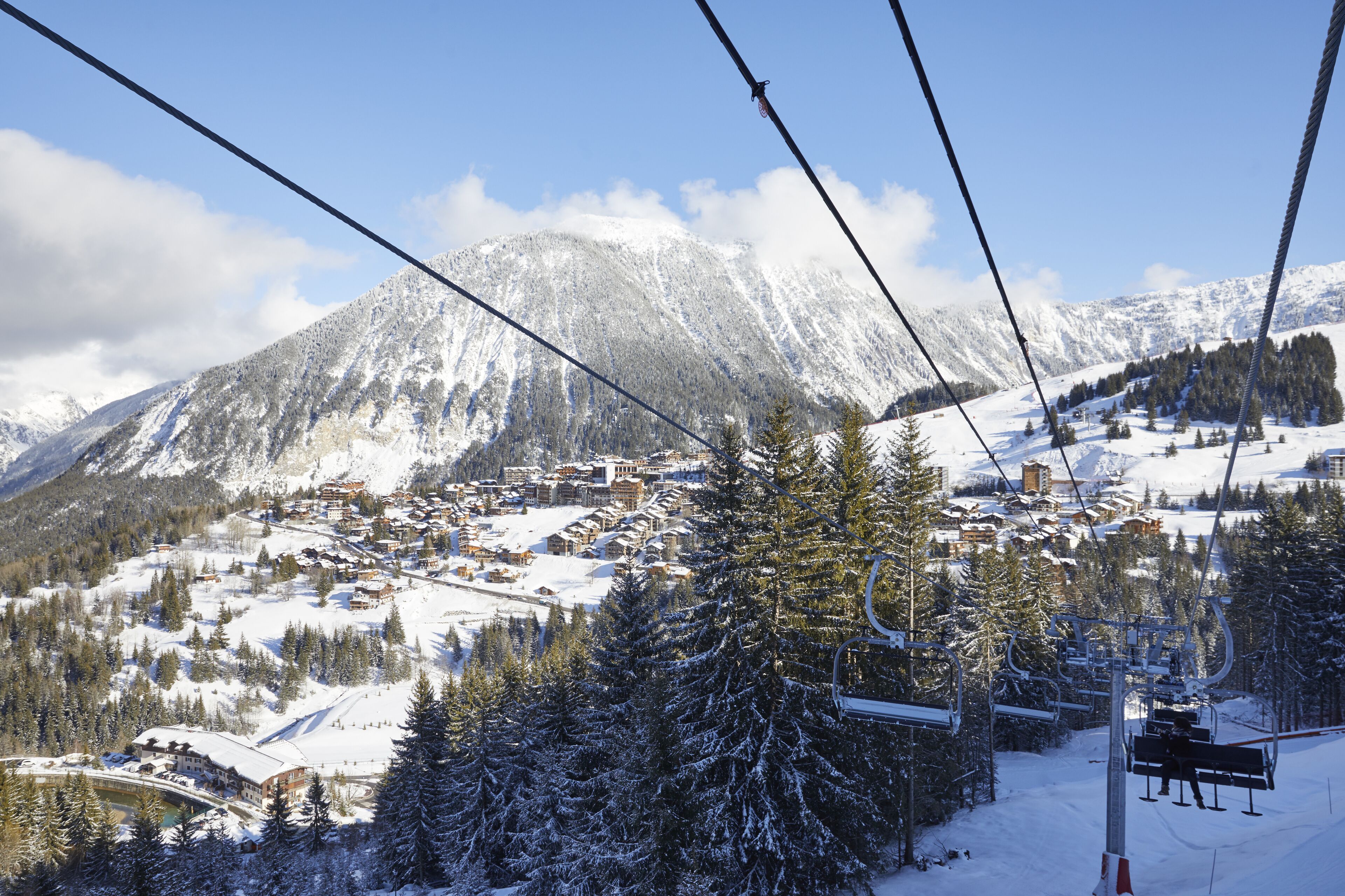 Eine verschneite Bergstadt mit Seilbahn, Häusern und Bäumen.