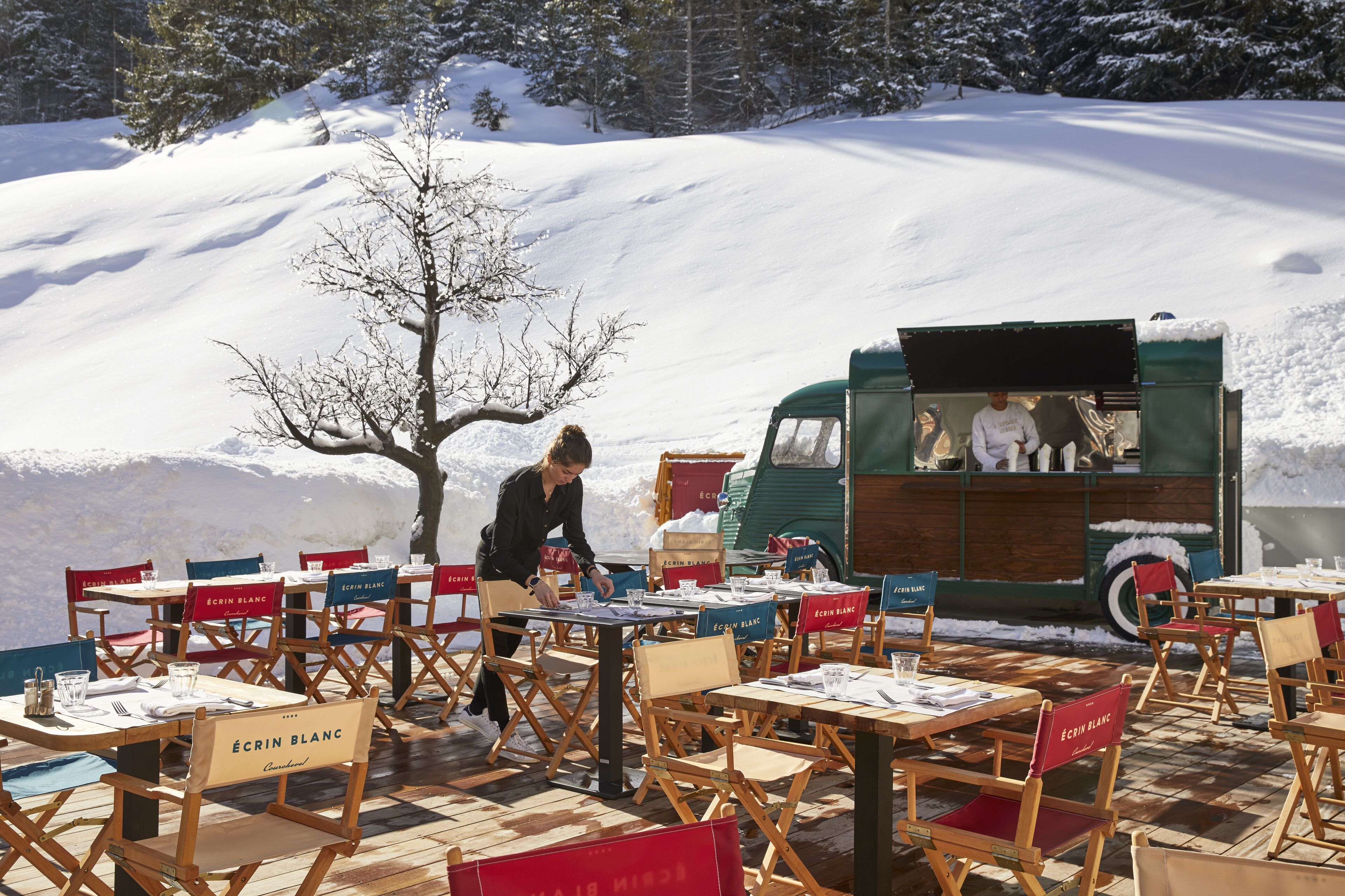 A snow-covered outdoor dining area with tables and chairs labeled "Écrin Blanc."