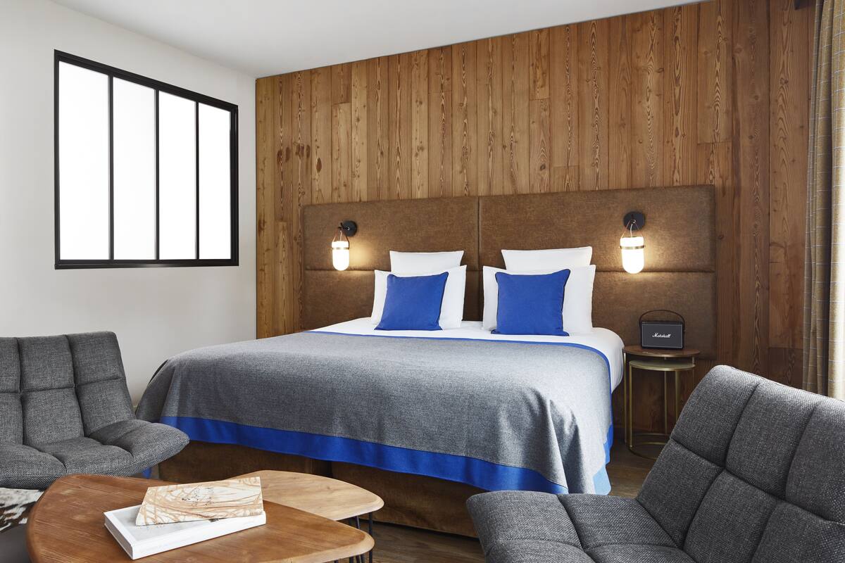 Camera d'albergo con un letto grande, due lampade sui comodini, una testata del letto in legno e vista sull'esterno attraverso una finestra.