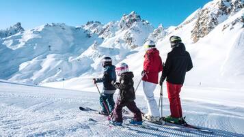 A group of people on a snowy slope with mountains in the background.