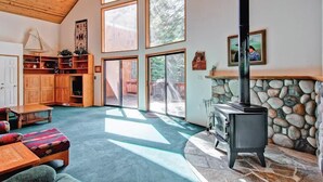 A spacious living area with a stone fireplace, large windows, and a wooden ceiling. - Yosemite View (Yosemite National Park)