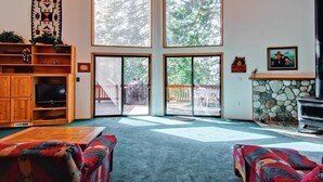 A spacious living room with a large window, a fireplace, and a television. - Yosemite View (Yosemite National Park)