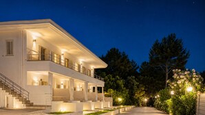 A modern two-story building with a balcony, a covered outdoor seating area, and a well-lit driveway. - Petra Maris B&B (Peschici)