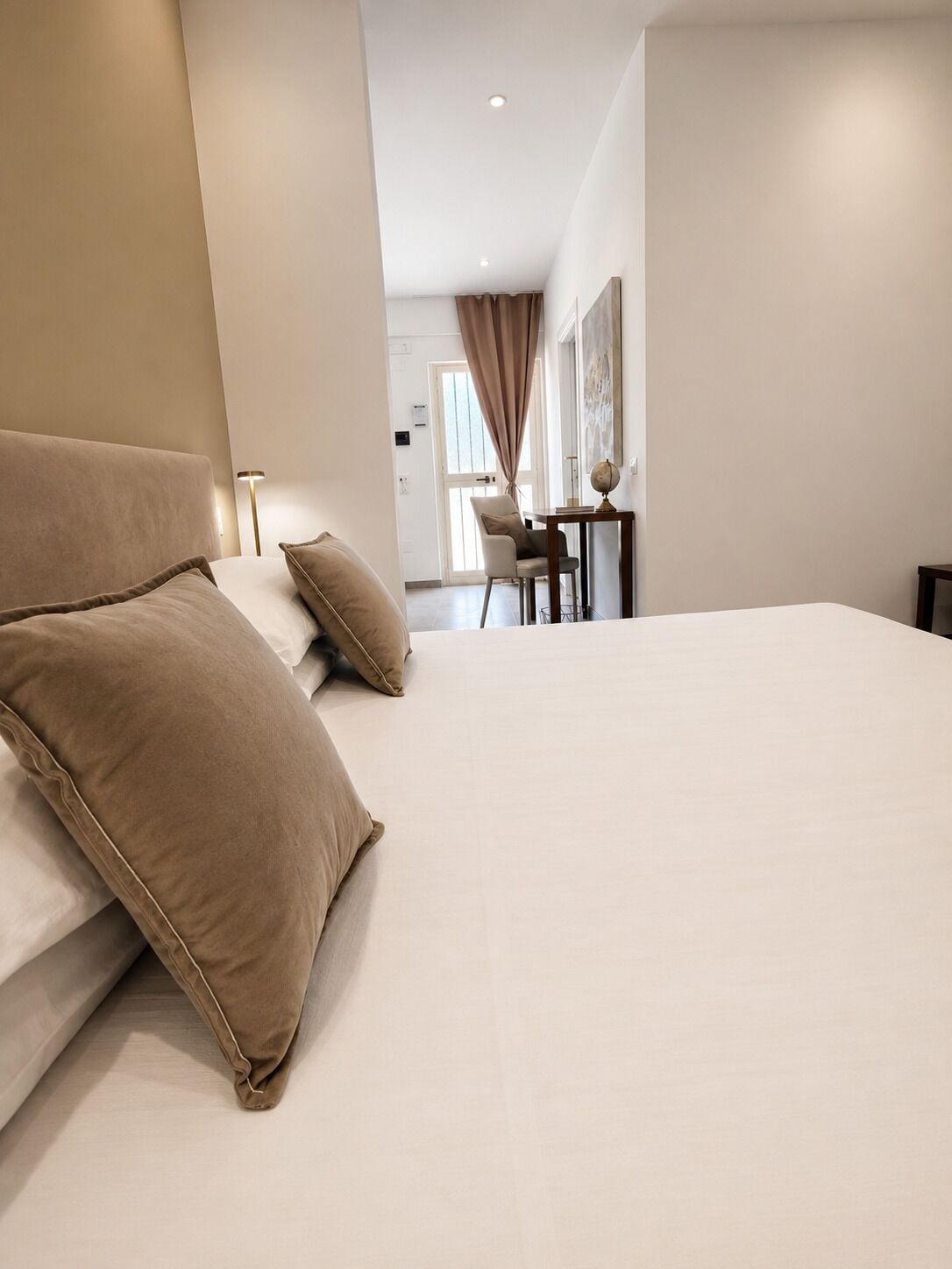 A modern hotel room with a large bed, a desk, and a chair.