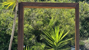 A wooden frame with a mirror, surrounded by rocks and plants. - Petra Maris B&B (Peschici)