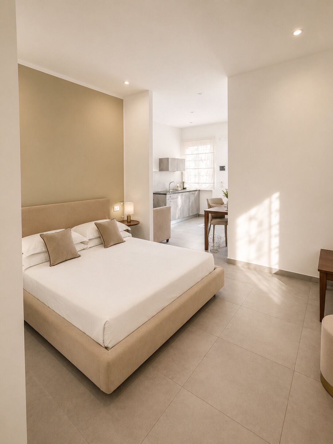 A modern hotel room with a large bed, a small kitchen, and a dining area.