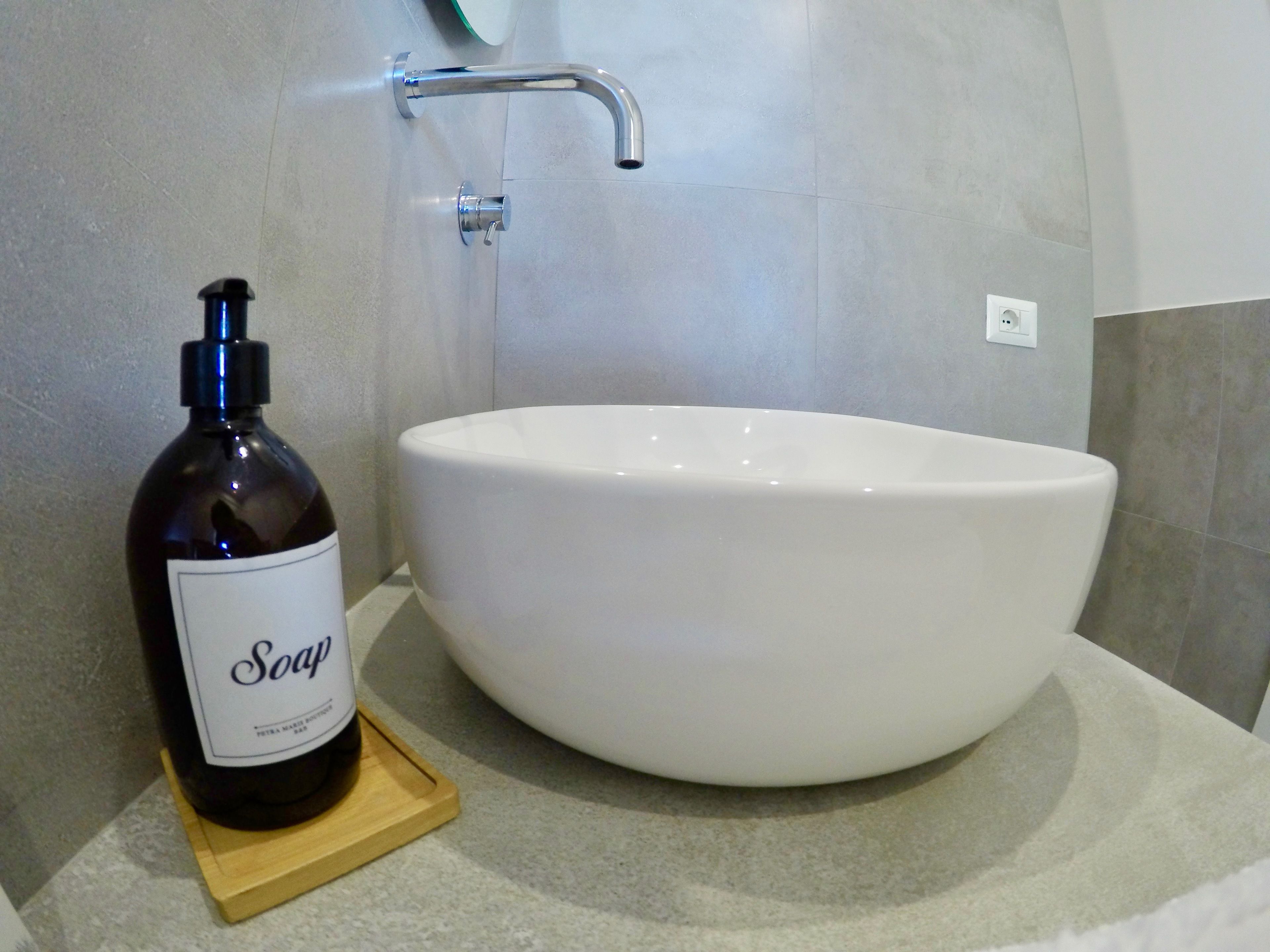 A bathroom with a white sink, a soap dispenser, and a faucet.