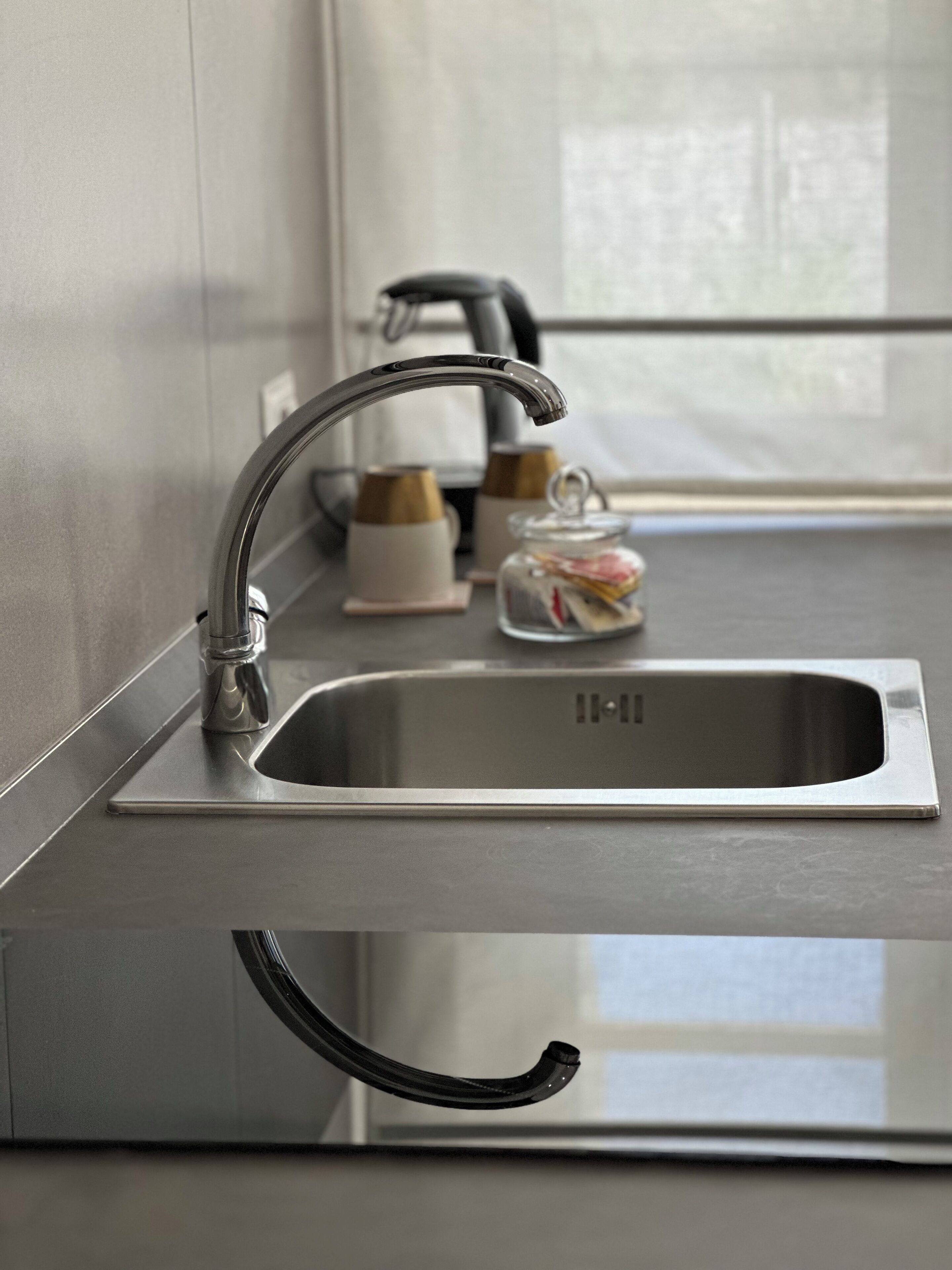 A modern kitchen with a stainless steel sink, a faucet, and a glass jar on the countertop.
