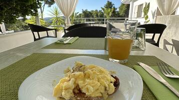 Una mesa con un plato de huevos revueltos y tostadas, un vaso de jugo de naranja y un mantel individual verde.