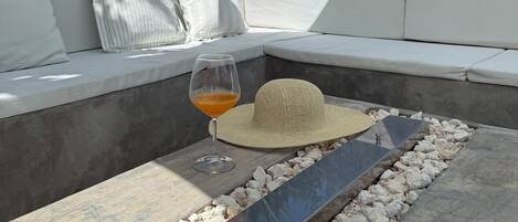 A modern outdoor seating area with a stone table, cushions, and a glass of drink.