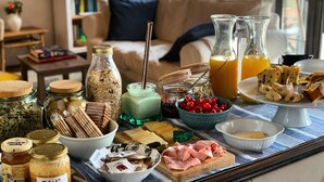 A breakfast spread on a table with various food items, including bread, cheese, and fruits, in a cozy living room setting. - Relais Valpolicella B&B (Marano di Valpolicella)